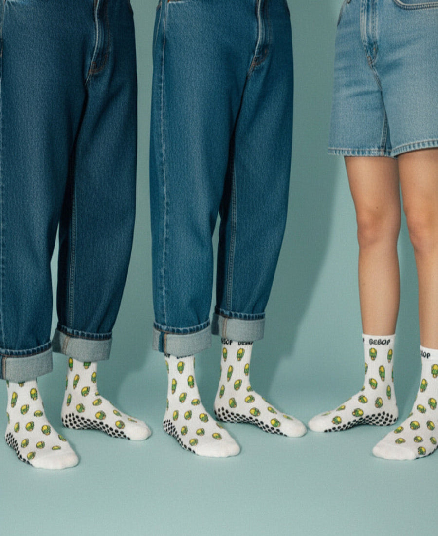 Three people wearing white socks with avocado pattern and blue jeans on a teal background